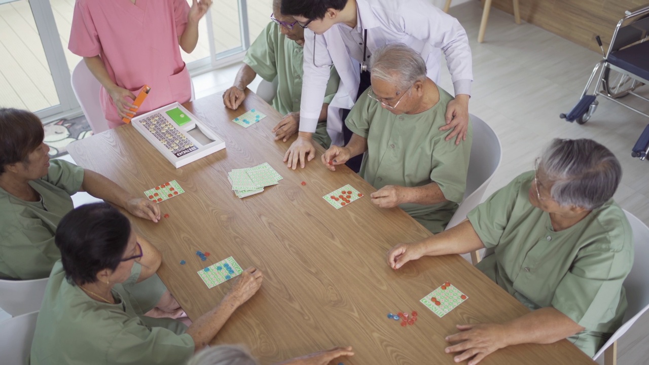 一群快乐的亚洲老人或退休老人与护士和医生在疗养院玩游戏的肖像。老年人生活方式活动娱乐。退休社区。卫生保健视频素材