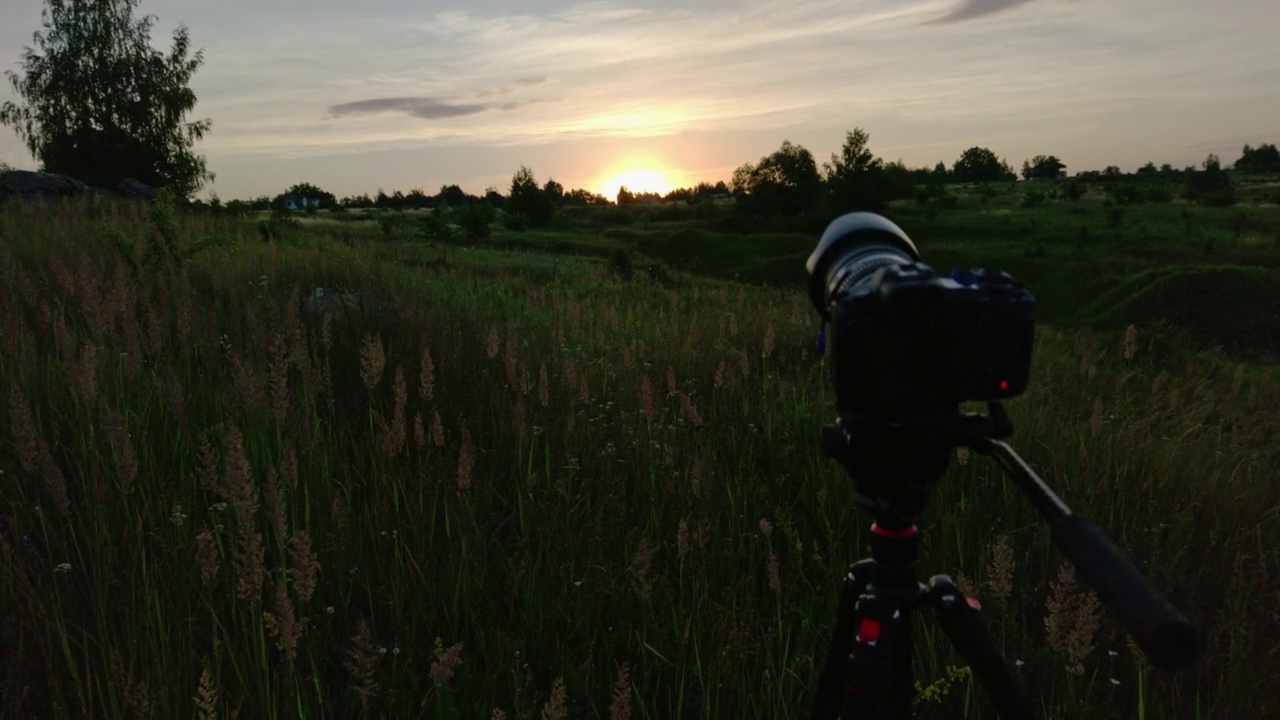 照相机在三脚架上拍摄夏天草地上的日出视频素材