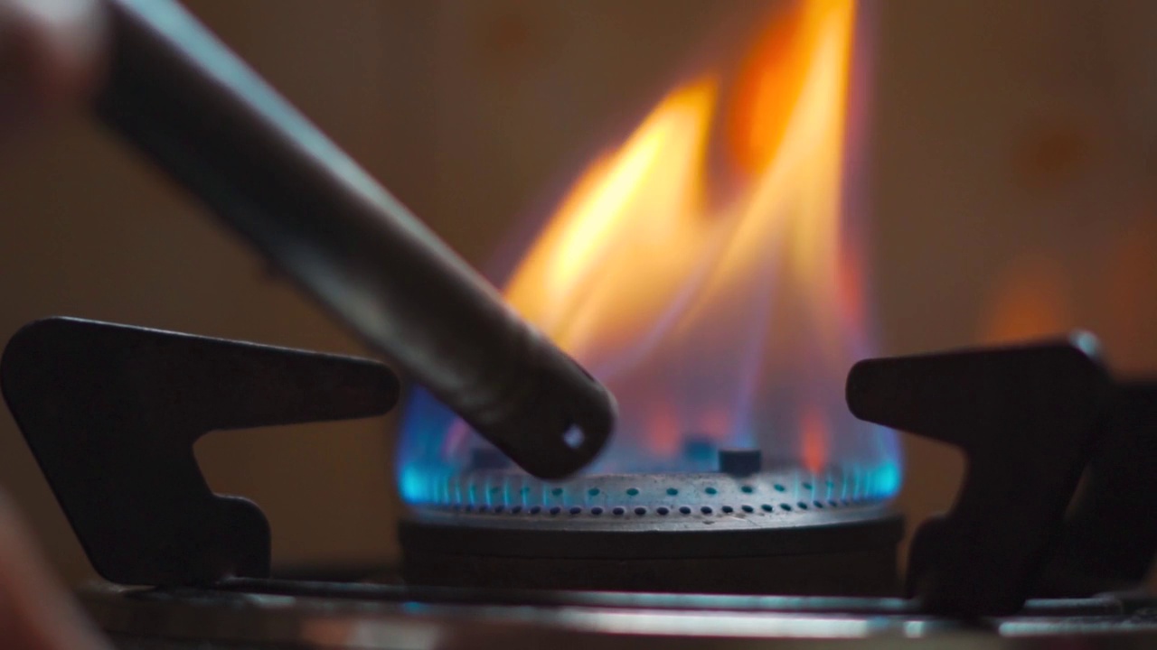 燃气灶的特写镜头打火机点燃炉子，蓝色的烹饪火焰。天然气炎症，闭合。印度女性在厨房点燃炉子做饭视频素材