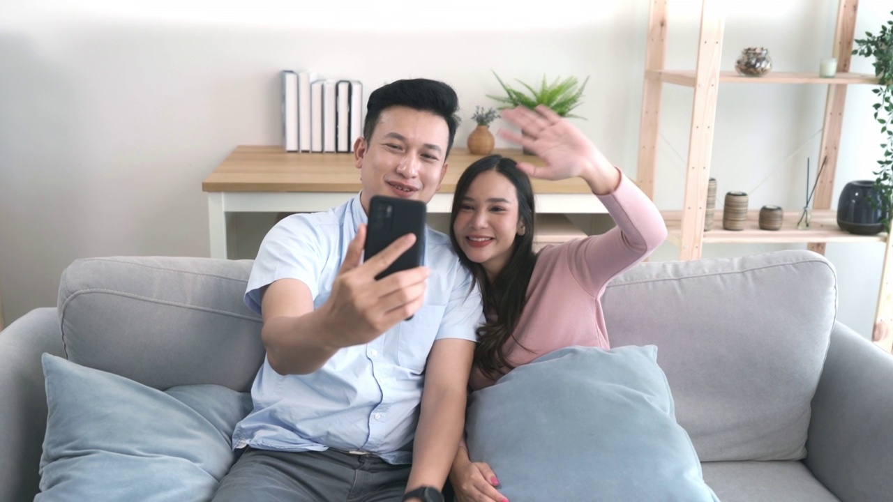 在公寓里，一对亚洲成年夫妇用智能手机看着屏幕。视频素材