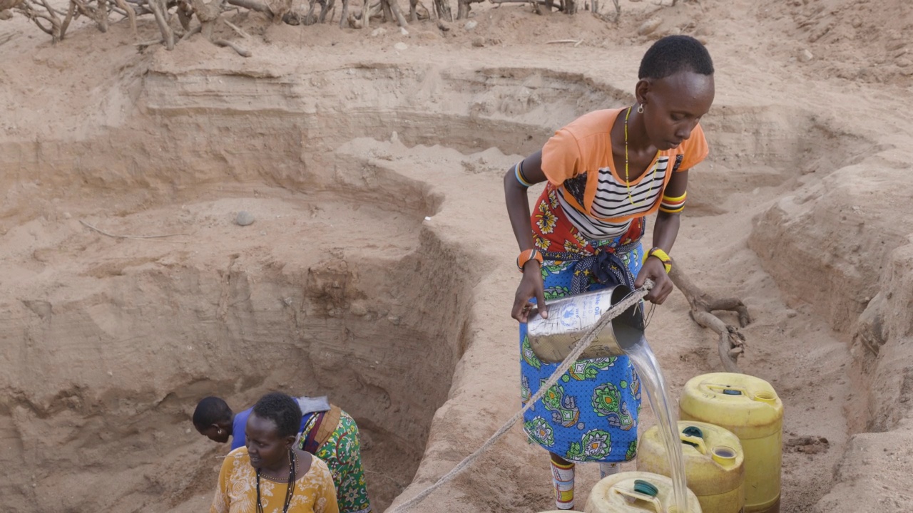 气候change.drought.water crisis.Close-up。由于持续干旱，一名非洲妇女用塑料容器从深井中汲水。肯尼亚视频素材