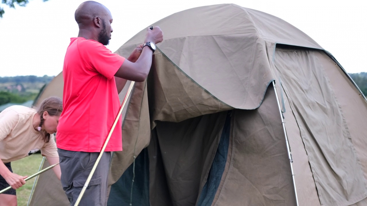 一名黑人和他的白人助手为过夜的游客搭建帐篷视频下载