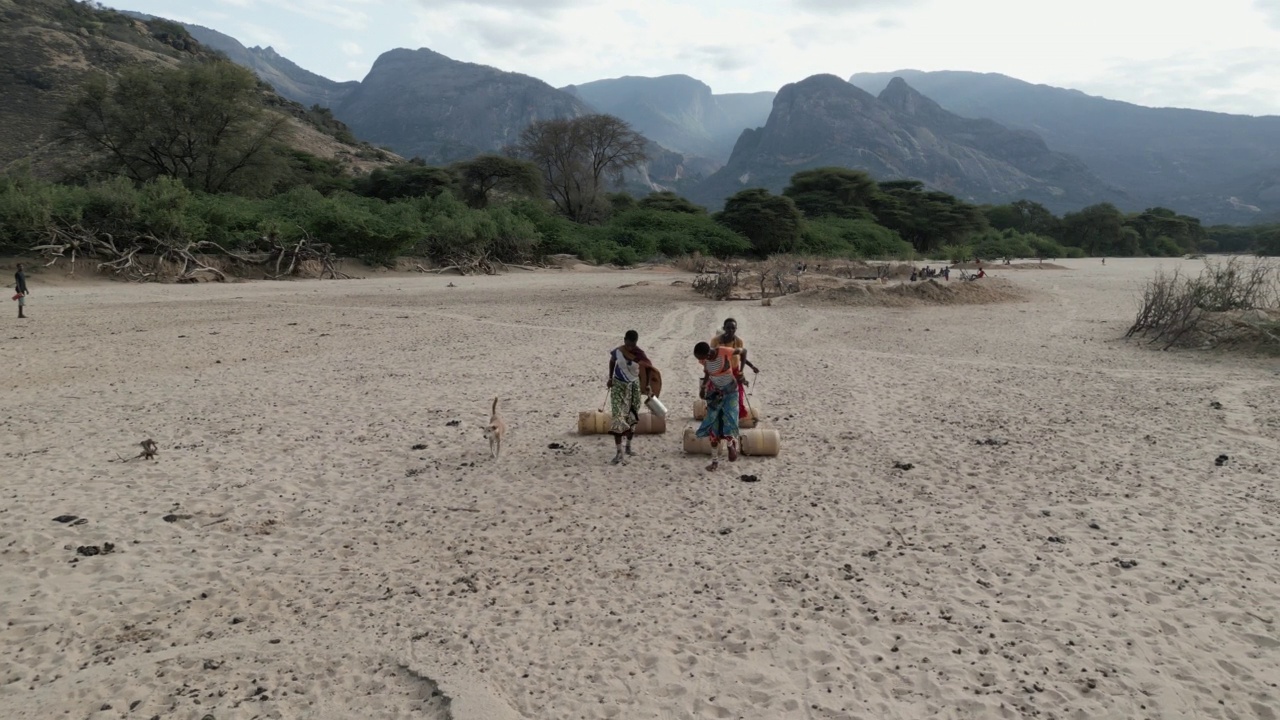 气候change.drought.water危机。特写侧视图。一名非洲妇女走着用塑料容器打水回家，这些塑料容器是从由于持续干旱而从深井中收集的。肯尼亚视频素材