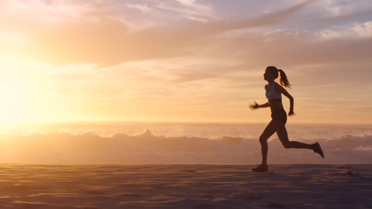 健康，积极和运动的女性跑步，慢跑和锻炼在夏天的日落在海滩上。一个精力充沛、意志坚定、运动健将的女人在海边训练，做有氧运动和短跑视频下载