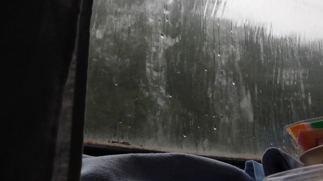 火车行驶时，雨滴落在肮脏的车窗上视频下载
