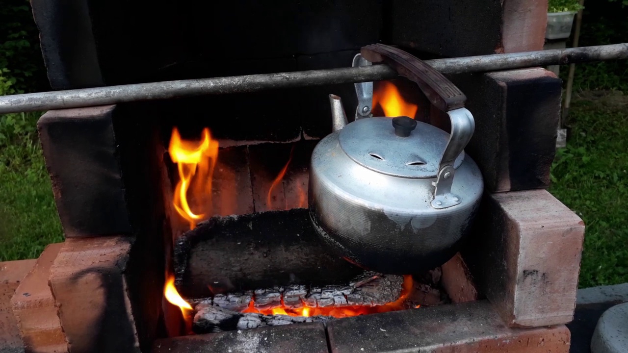 水壶在花园里或大自然中简单的砖砌壁炉上的火上沸腾视频素材