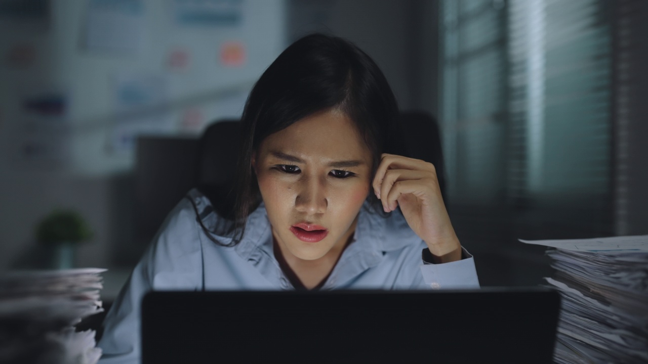 沮丧的女团队领导/商务女性在笔记本电脑上工作，检查她的团队工作到深夜，对商业报告中的错误感到愤怒。视频素材