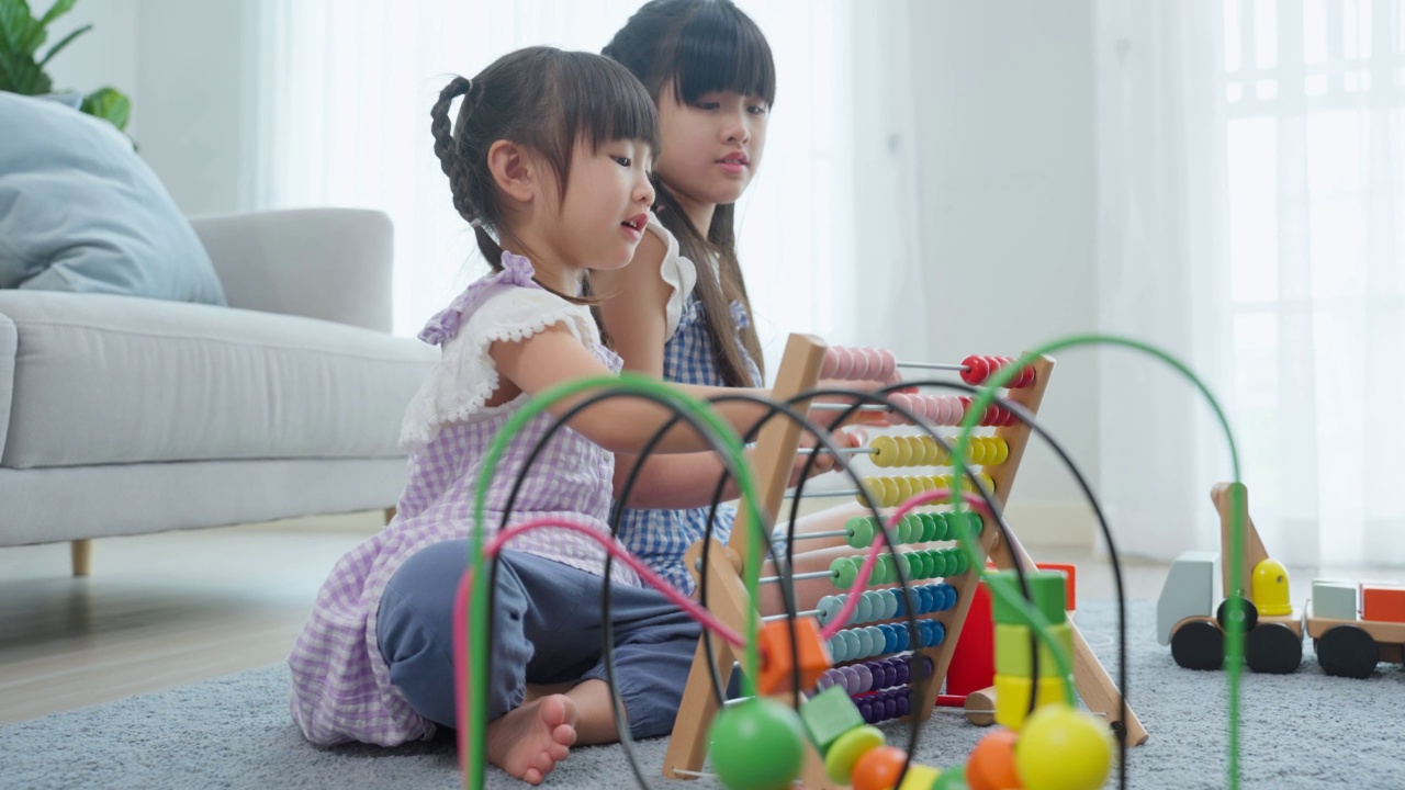 亚洲年轻女孩兄弟姐妹一起在家里的客厅玩玩具。小可爱的孩子妹妹坐在地板上，度过空闲时间做创意有趣的活动在家里度假。视频素材