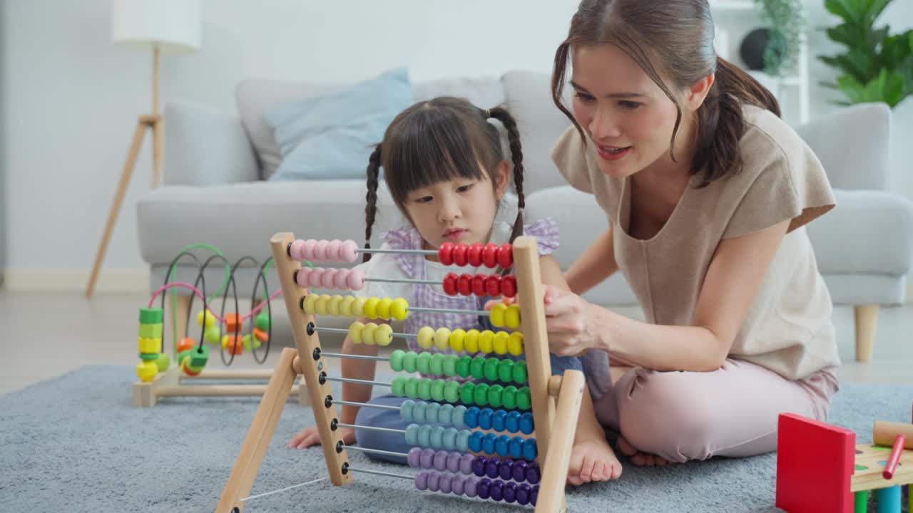 亚洲美丽慈爱的妈妈在家里和女儿玩教育游戏。漂亮的女人父母花空闲时间与年轻的小女孩孩子花时间学习和发展技能与儿童的玩具。视频素材