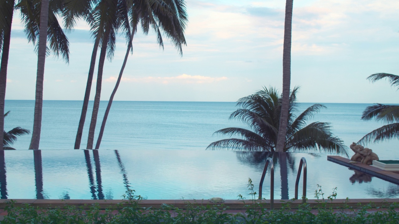 海边的游泳池，椰子树和蓝天，适合在夏天旅行和放松。视频素材