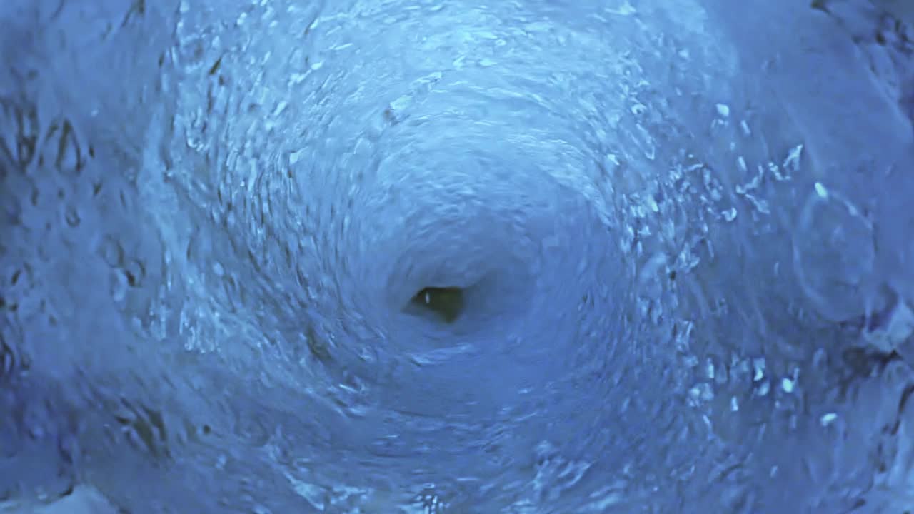 俯视旋转液体在一个蓝色调上的慢动作。视频下载