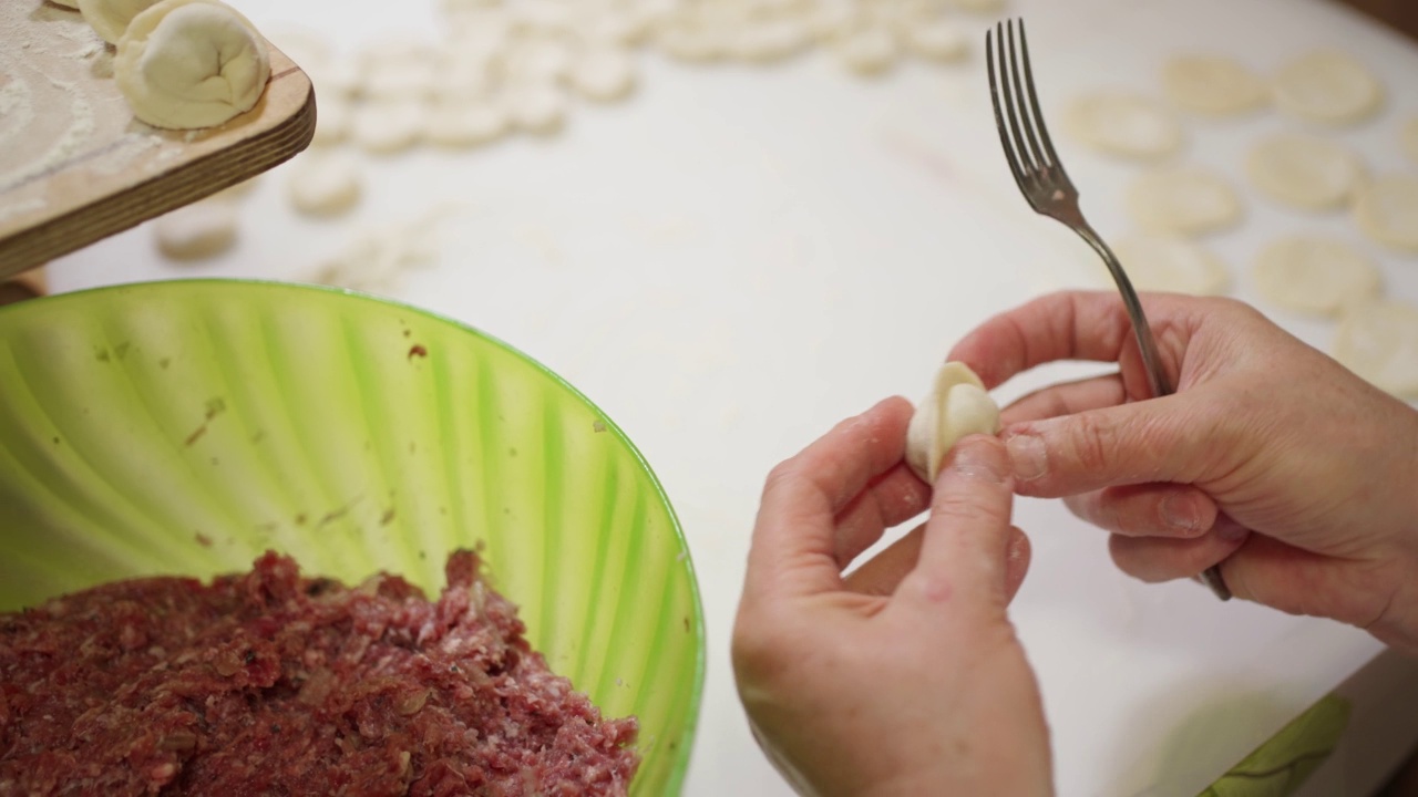 女性手用叉子从大碗里挑肉末，然后把饺子馅放进面团里。自制的粽子,手工制作的视频下载