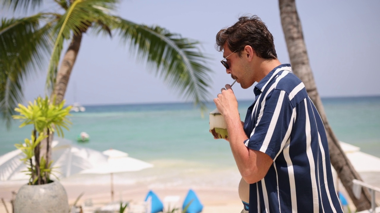 白种人，一边喝着椰子，一边欣赏海滩上的海景视频素材