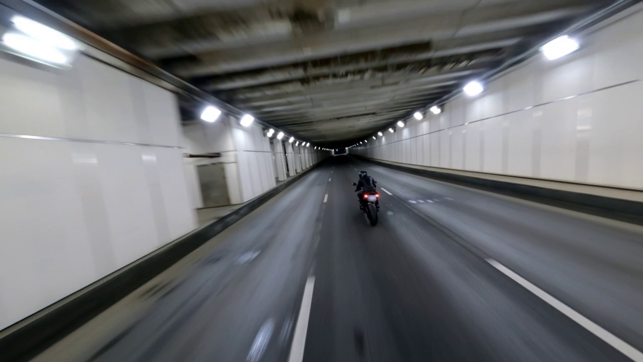 快速灰色宝马摩托车在建设中的城市道路上高速行驶，fpv无人机拍摄视频下载