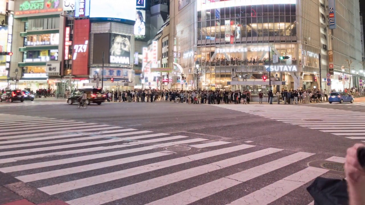 在日本东京，许多行人和车辆在夜间穿过路口的涩谷十字路口视频素材