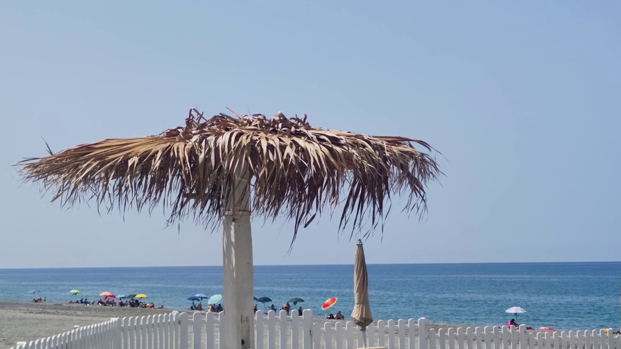 以大海为背景的沙滩草伞。意大利南部卡拉布里亚海滩的海景。白天的海滩风景。沙滩。视频素材