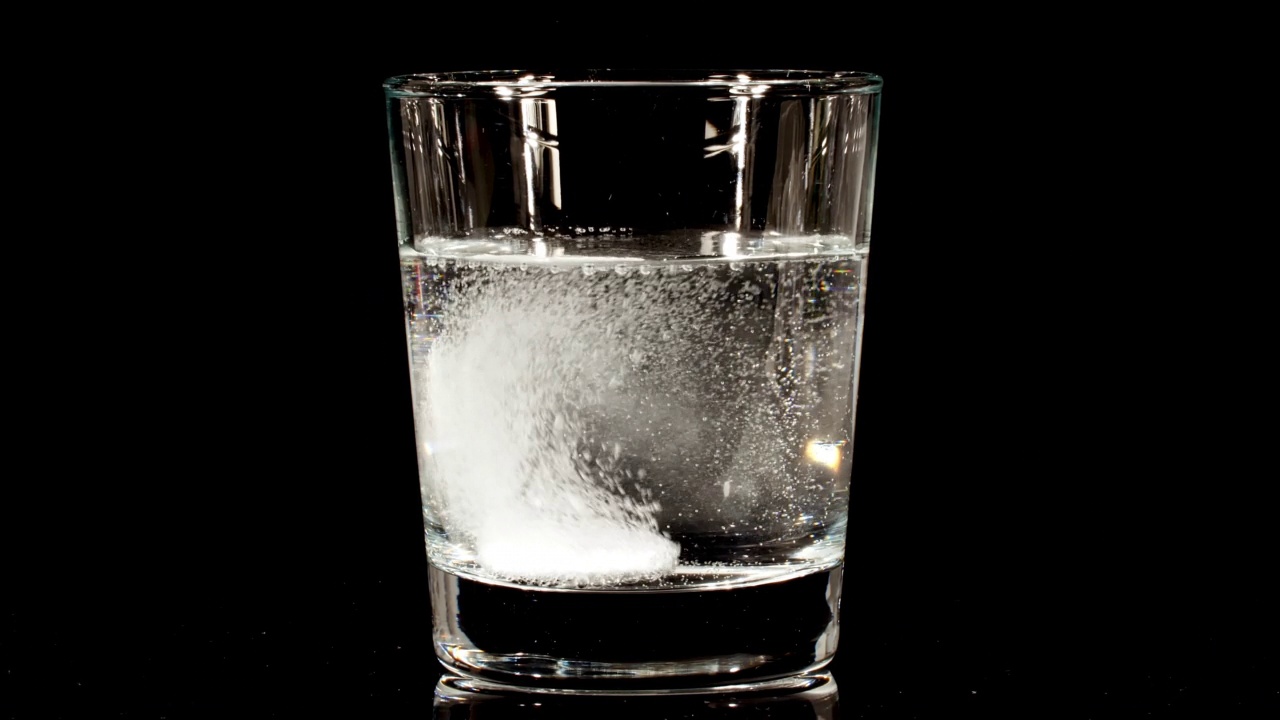阿司匹林药片落在玻璃杯里，黑底有水。发泡片阿司匹林。医学概念、保健、治疗。慢动作视频下载
