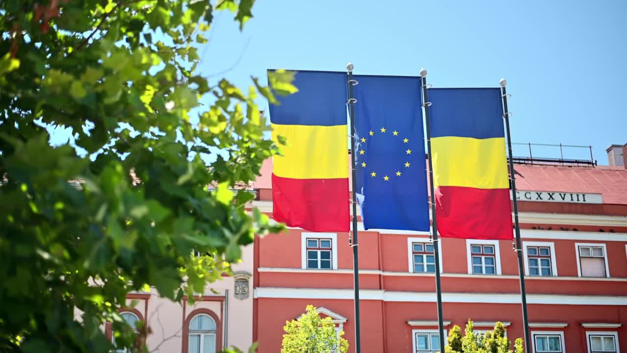罗马尼亚克卢日中心的两面国旗和一面欧盟国旗。背景是经典的建筑视频下载