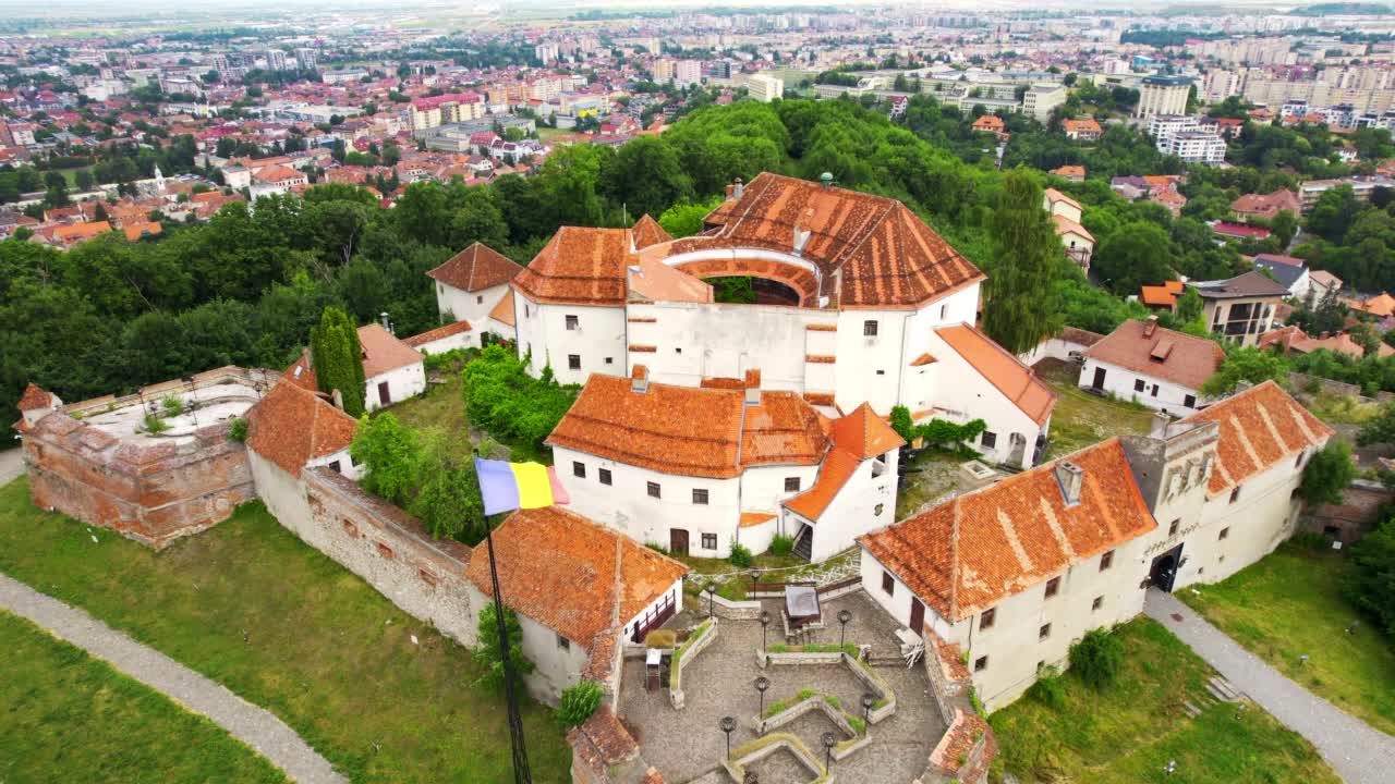 罗马尼亚布拉索夫城堡的无人机视图。中世纪要塞和山顶上的国旗。周围的建筑和绿树视频下载