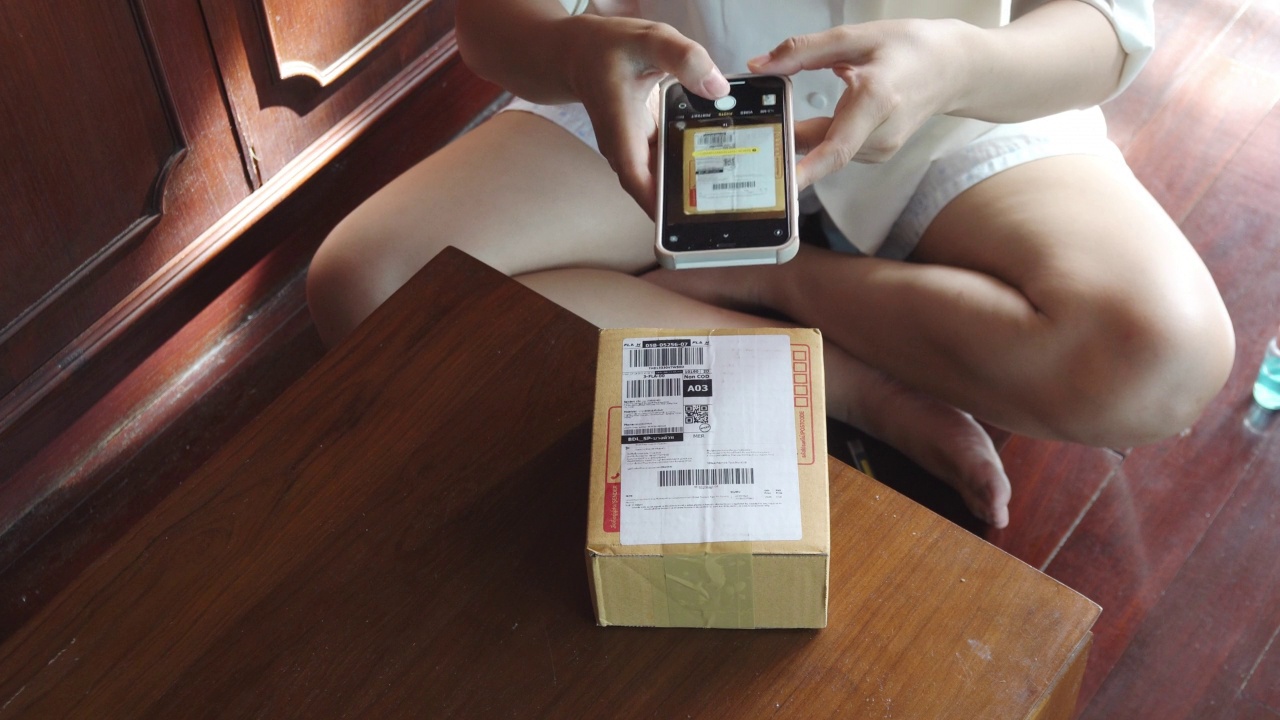 亚洲妇女移动扫描条形码包裹。视频下载