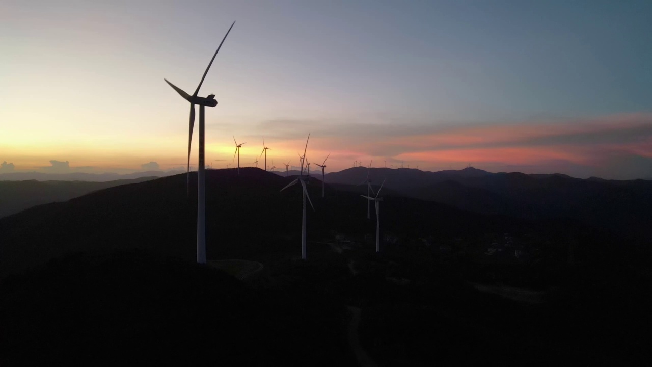 山顶上落日余晖下风力涡轮机的剪影视频素材
