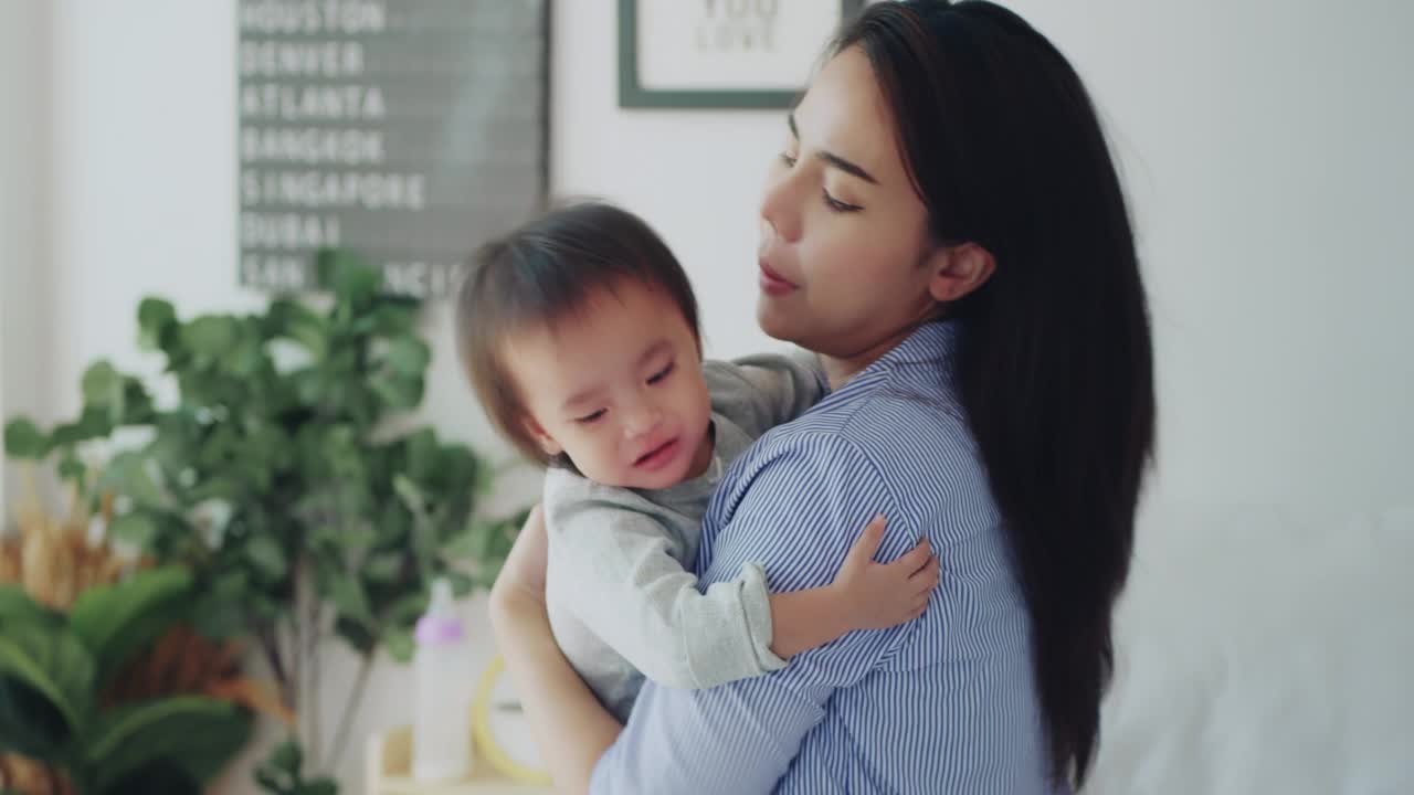 亚洲新妈妈安慰她哭泣和生病的女儿在卧室视频素材