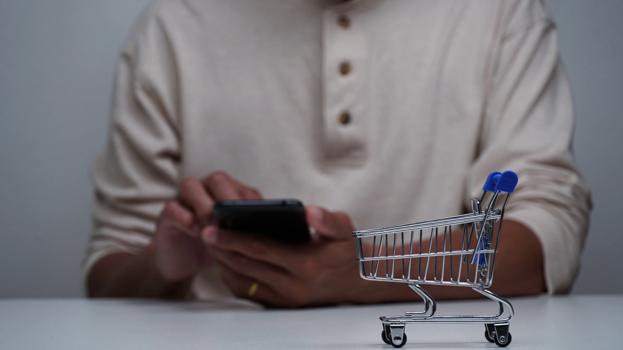 定格动作一个男人用智能手机网购，购物车购物移动。视频下载