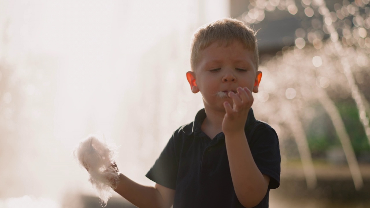 有趣的蹒跚学步的小男孩把一大块棉花糖放进嘴里视频下载