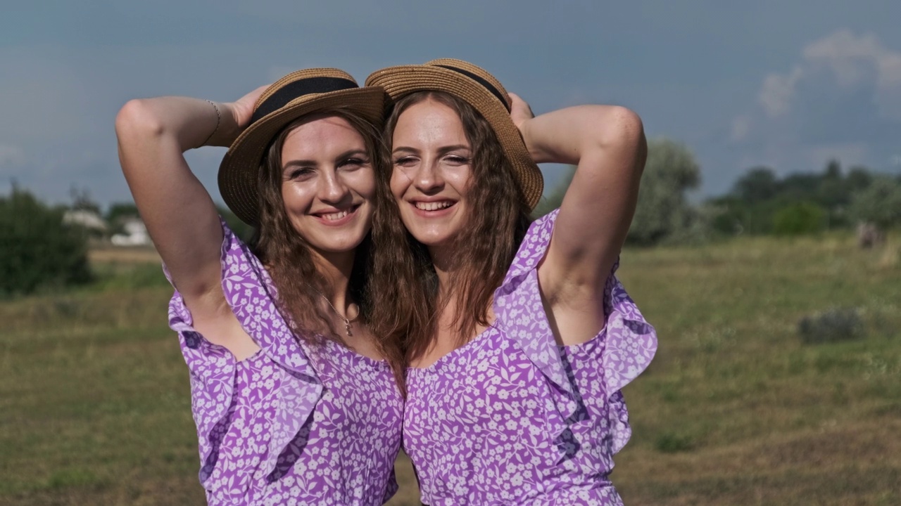 肖像两个年轻的双胞胎女孩在相同的裙子看相机在自然视频下载