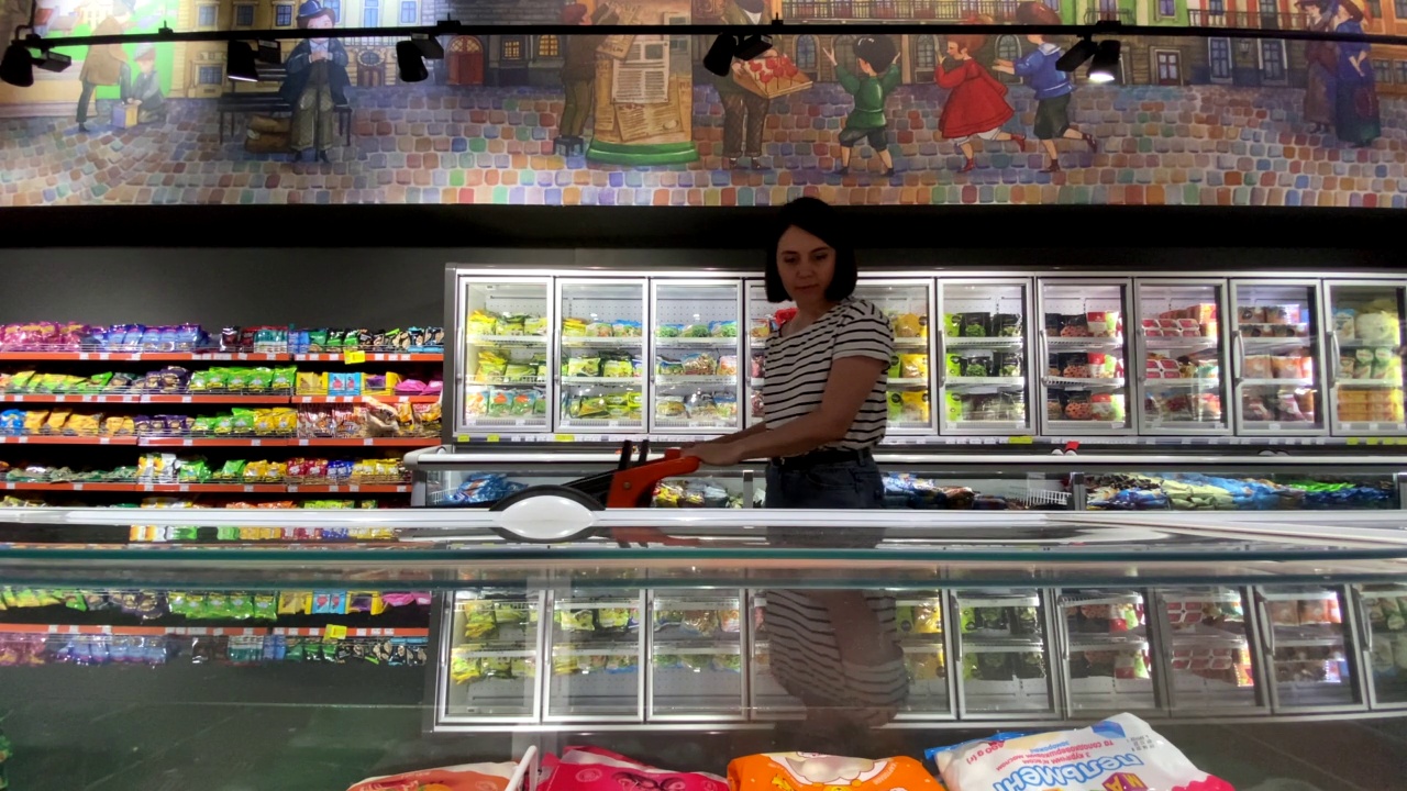 在杂货店从冰箱里拿东西的女人视频素材