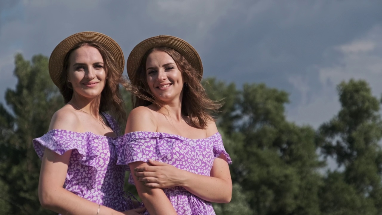 肖像两个年轻的双胞胎女孩在相同的裙子看相机在自然视频下载