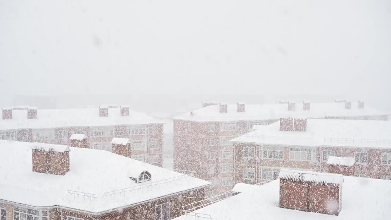 白色的雪落在住宅的屋顶上。冬天，暴风雪，雪和冰。雪地里的天空和公寓楼的屋顶。恶劣的天气条件，天气慢动作镜头视频素材