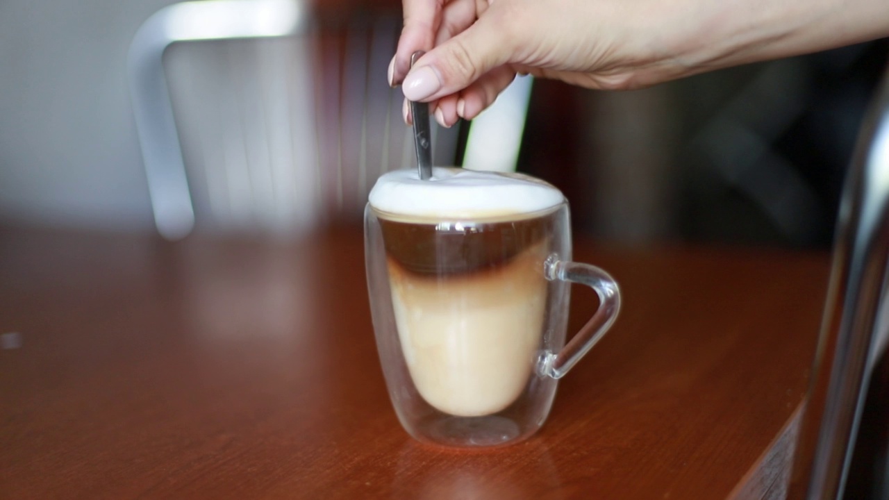 用勺子在玻璃杯中搅拌热咖啡拿铁的浓泡沫视频下载