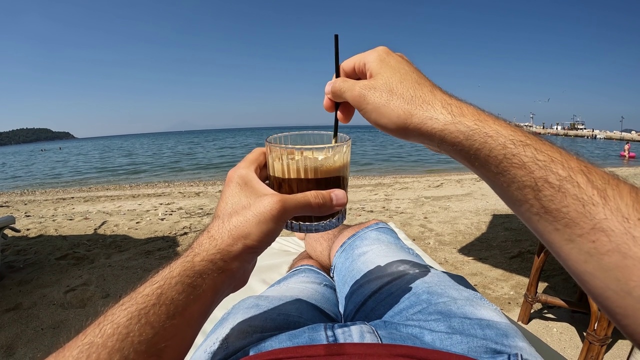 男人在海滩的躺椅上喝着冰咖啡视频素材