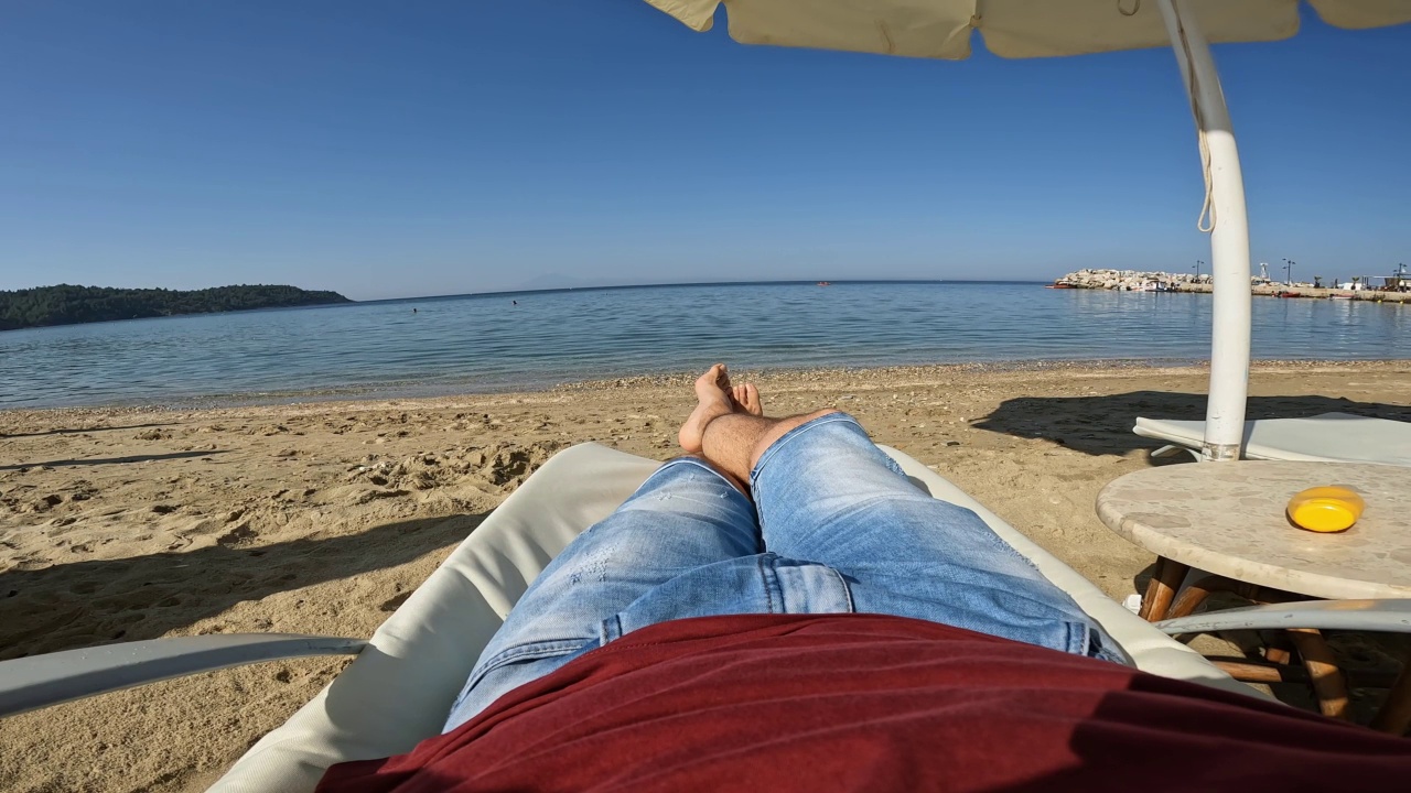 一个年轻人在海滩的躺椅上休息视频素材