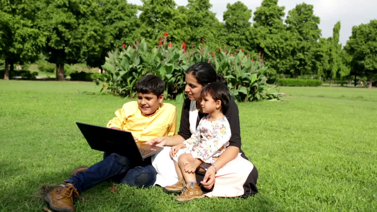 两个孩子一起在公园户外使用笔记本电脑视频素材