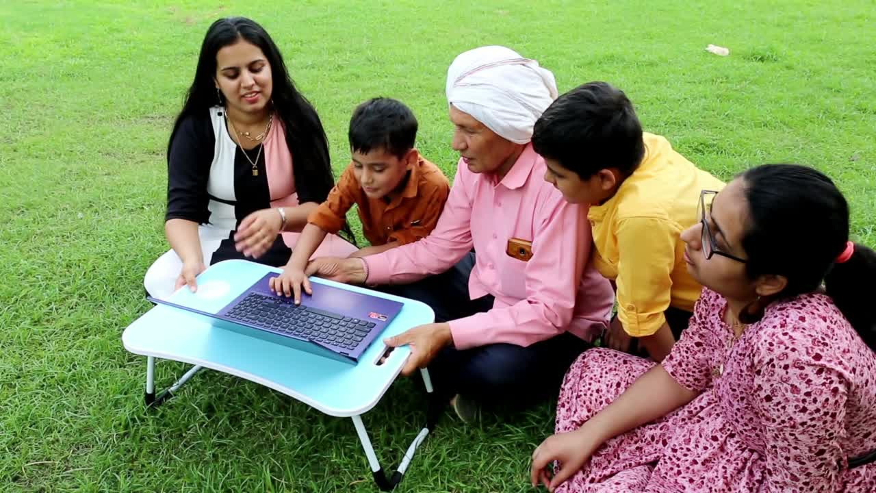 印度家庭在公园里一起使用笔记本电脑视频素材