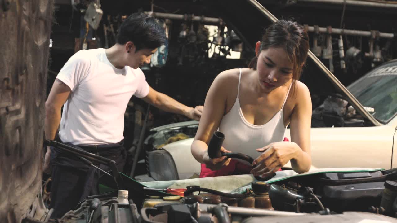 一名亚洲妇女在车库里修理汽车引擎。视频素材