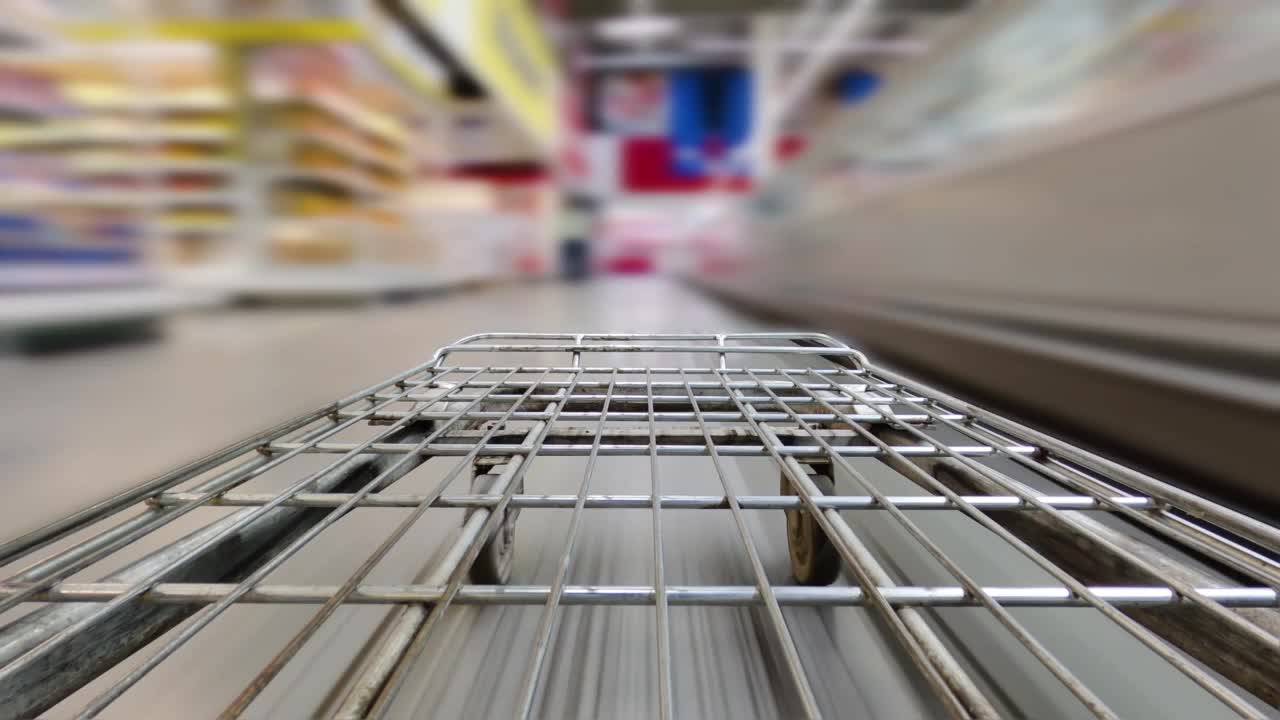 超市或仓库里的购物车在一排排货架和货架间穿行。散焦模糊背景。购物的概念。视频下载