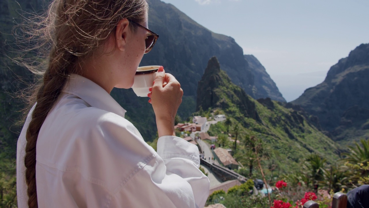 年轻女子喝咖啡，背景是马斯卡峡谷。特内里费岛，加那利群岛，西班牙视频素材