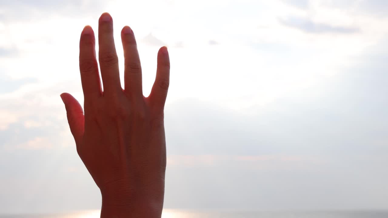 女性的手触摸着太阳，夕阳在指间划过渡海视频素材