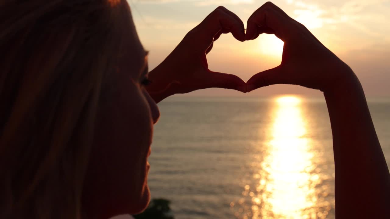 落日时分，大海上，女人的手伸出爱心的形状视频素材
