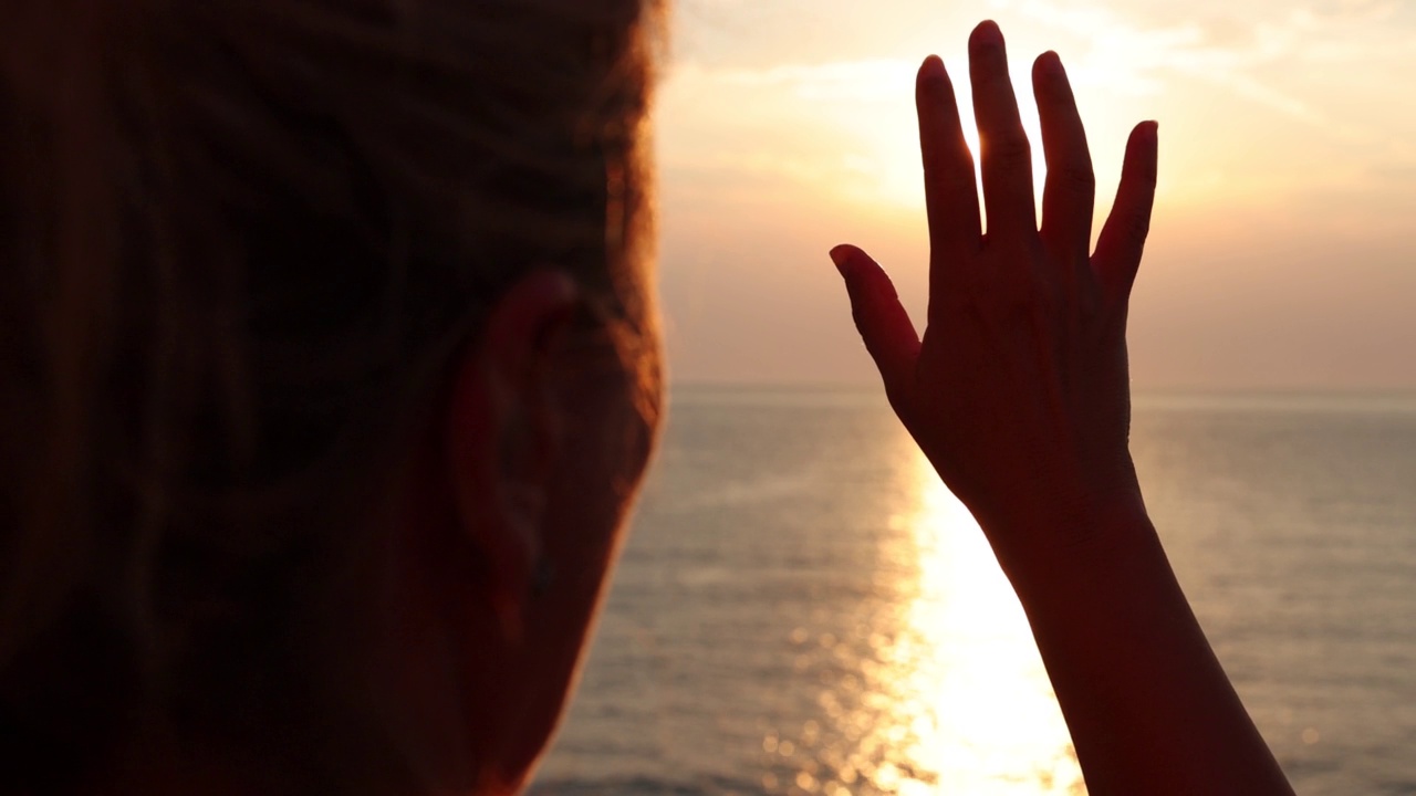 女性的手触摸着太阳，夕阳在指间划过渡海视频素材