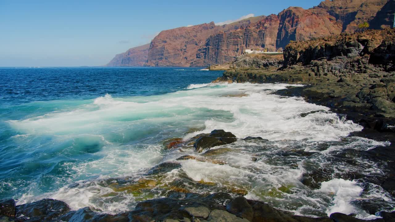 从加那利群岛特内里费岛的Acantilados de Los Gigantes海岸线欣赏著名的悬崖和海景。阳光明媚的一天。大浪拍打着前景中的岩石海岸。视频素材