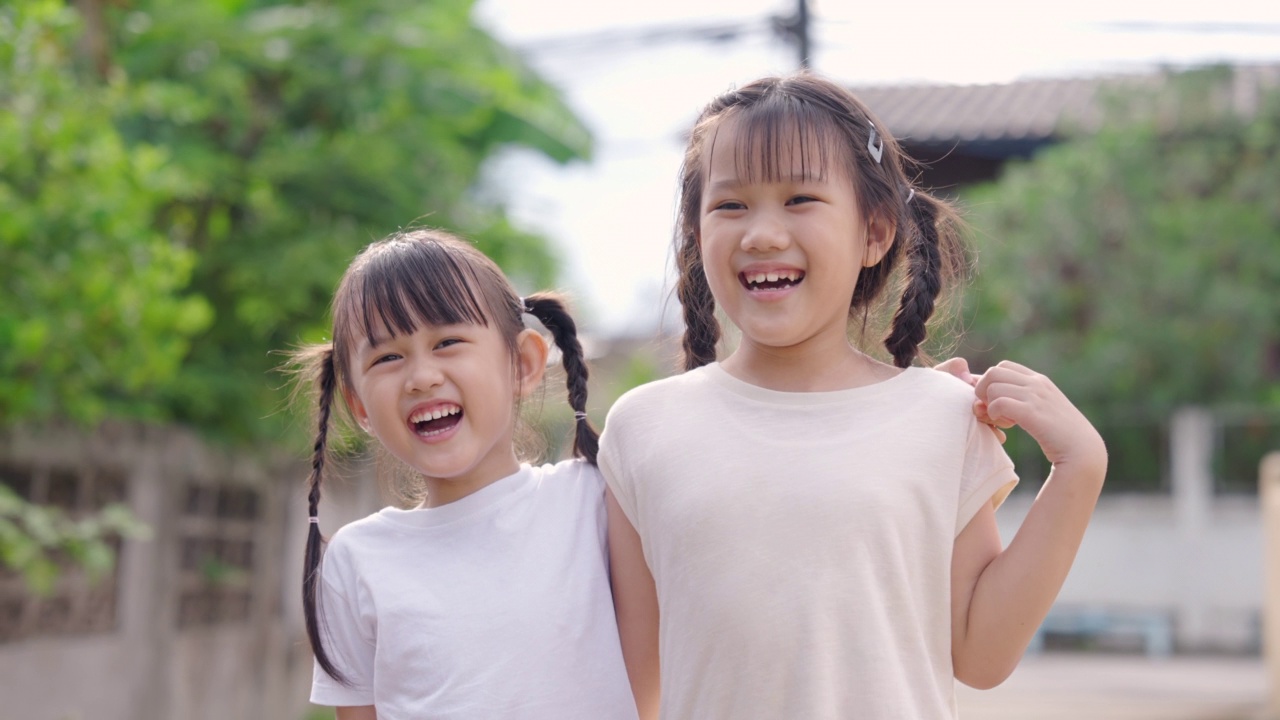 两个年幼的亚洲女孩在自然环境中灿烂地微笑。视频下载
