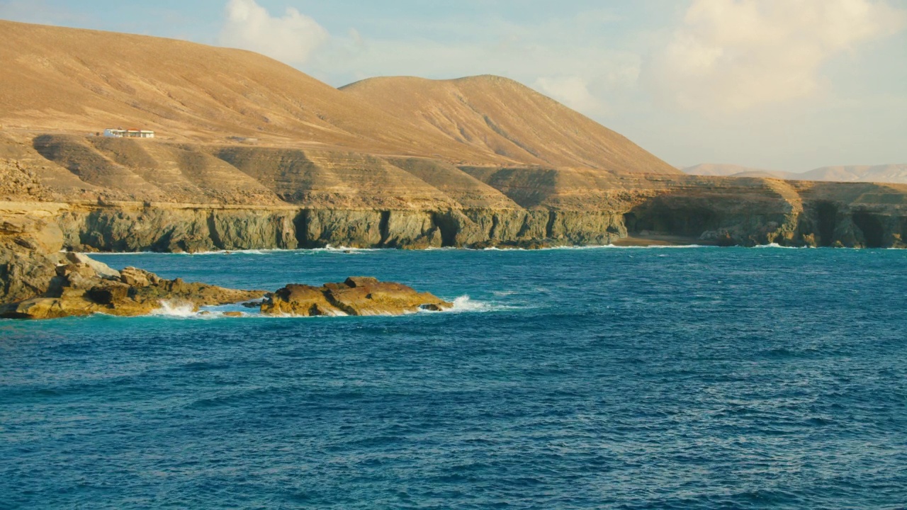 西班牙加那利群岛富埃特文图拉的阿朱伊镇的岩石和悬崖。蔚蓝平静的海浪。Picteresque壮观的4k电影拍摄。视频下载