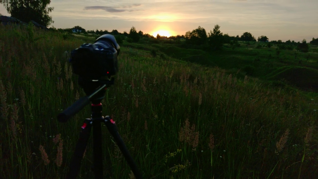 照相机在三脚架上拍摄夏天草地上的日出视频素材