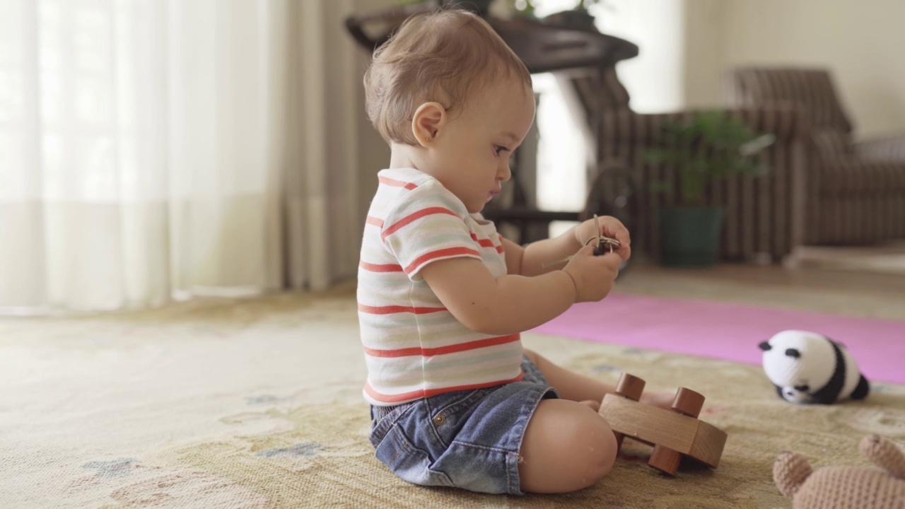 可爱的小女婴坐在家里玩钥匙和玩具视频素材