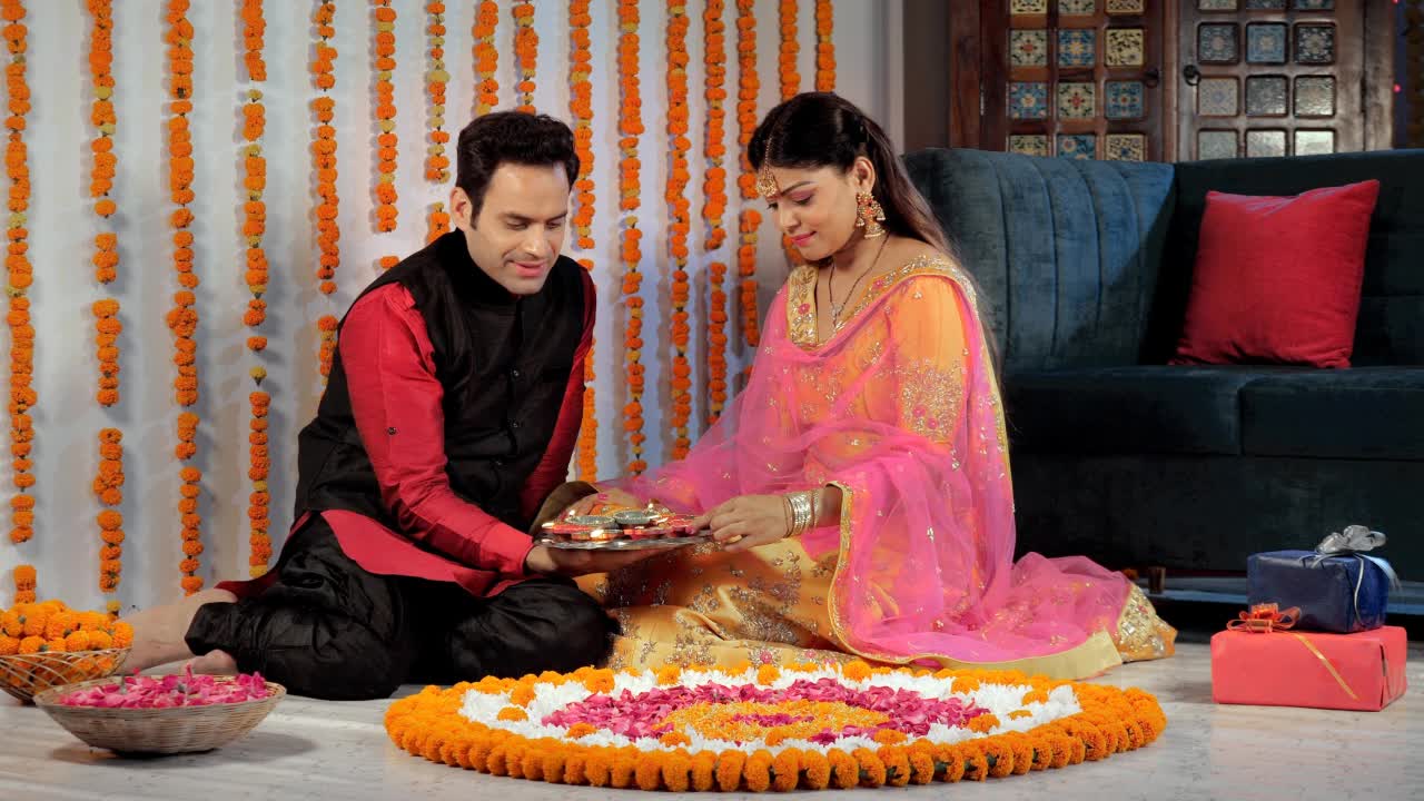 一对中年夫妇在家里用明亮的彩色Diyas装饰Rangoli视频素材