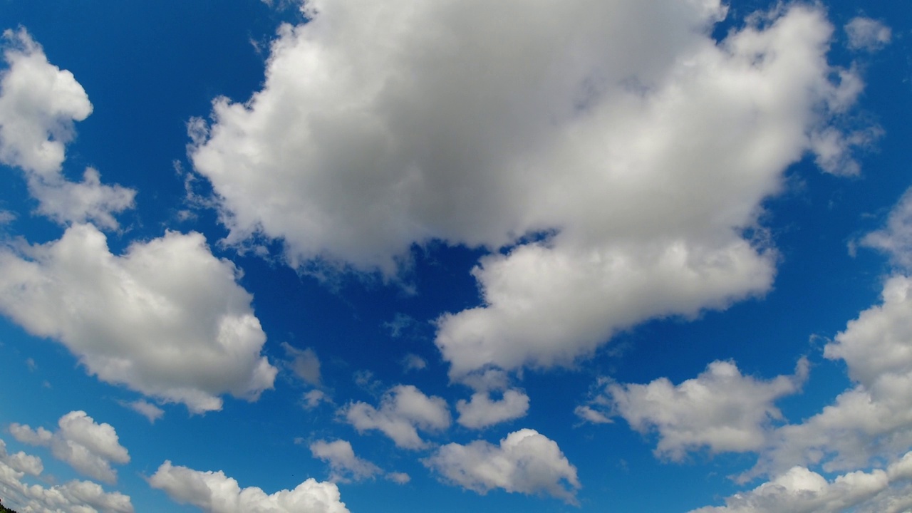 在一个阳光明媚的夏日，白色蓬松的积云从右到左快速移动。视频素材